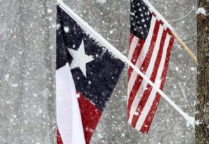 Texas flag and American flag with snow falling.