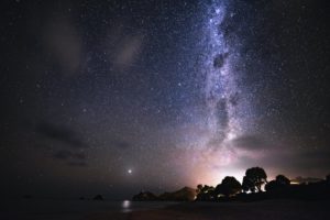 Photo of the Milky Way Galazy as seen from New Zealand with sky glow in the distance, representing the purpose of SB 52, working to protect dark skies from light pollution.
