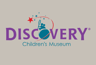 Discovery Children's Museum logo. The 'O' in Discovery shows two children sitting on the moon with a net trying to catch a red shooting star.