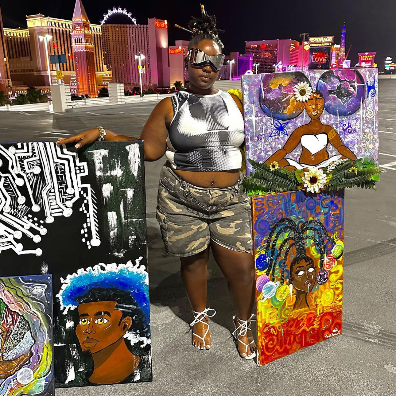 Bonee' Harden a.k.a. Art by Boneezy, displaying her artwork with the Strip skyline behind her.