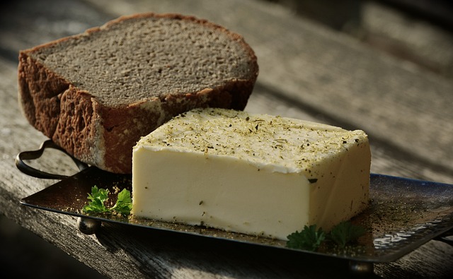 Tray of butter with herbs and a thick slice of bread. 